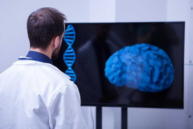 Młody chirurg mózgu patrzy na mózg pacjenta po operacji. Lekarz przy użyciu nowoczesnej technologii ze szpitala.