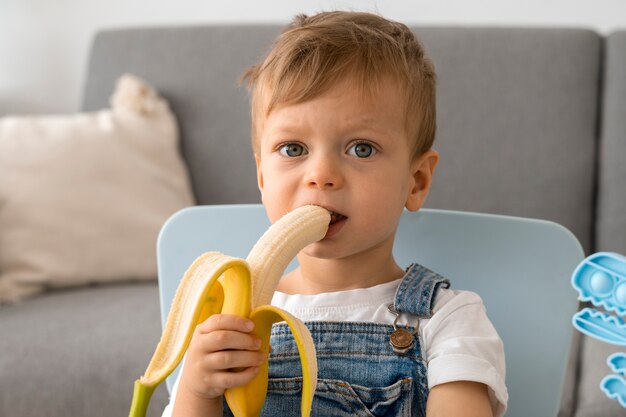 Młody chłopak je banana w domu