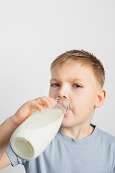 Młody chłopak pije mleko z butelki