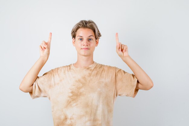 Młody chłopak teen wskazując w t-shirt i wyglądający pewnie. przedni widok.