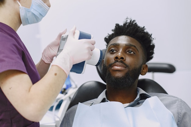 Młody człowiek afroamerykanin. Facet odwiedzający gabinet dentystyczny w celu zapobiegania jamy ustnej. Mężczyzna i znany lekarz podczas kontroli zębów.