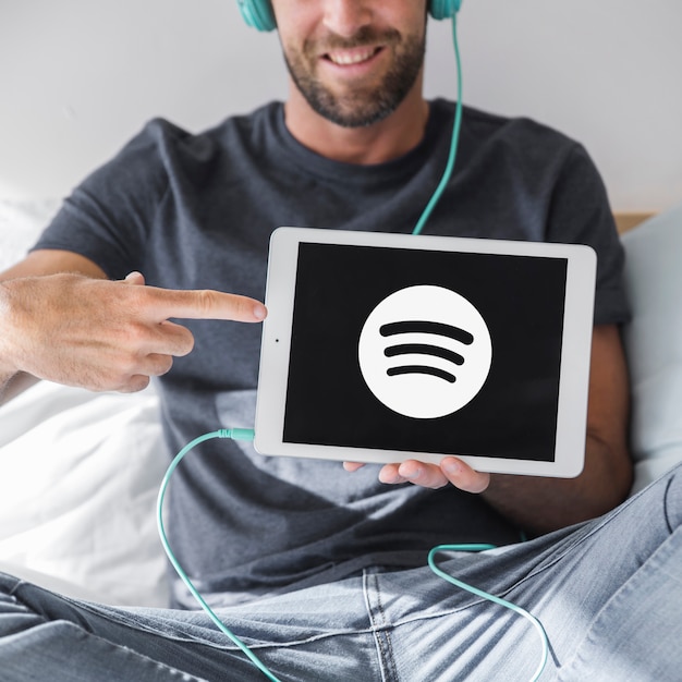 Bezpłatne zdjęcie młody człowiek gospodarstwa tabletki z aplikacji spotify