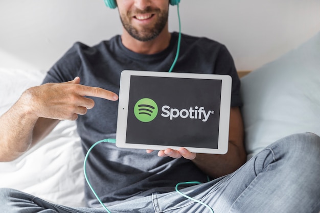 Bezpłatne zdjęcie młody człowiek gospodarstwa tabletki z aplikacji spotify