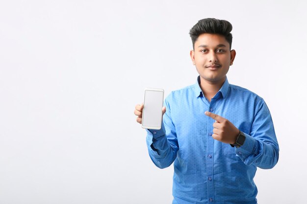 Młody człowiek indyjski pokazując ekran smartfona na białym tle.