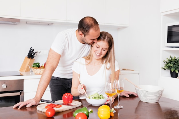 Młody człowiek kocha jego żony przygotowywa sałatki w kuchni