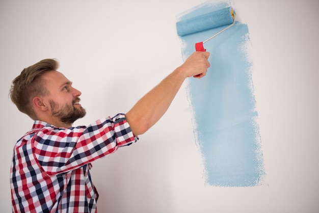Młody człowiek maluje niebieską ścianę
