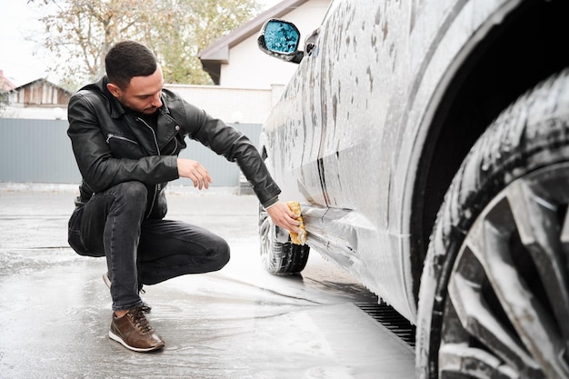 Młody Człowiek Myje Samochód Na Stacji Myjni Samochodowej Na Zewnątrz