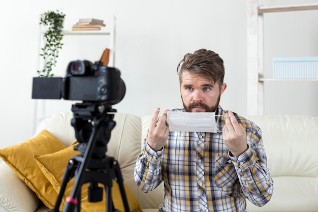 Młody człowiek nagrywa wideo w domu z maską