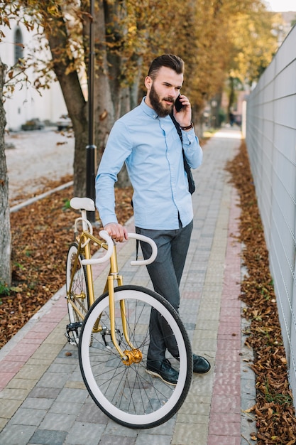 Bezpłatne zdjęcie młody człowiek opowiada na telefonie blisko ono fechtuje się