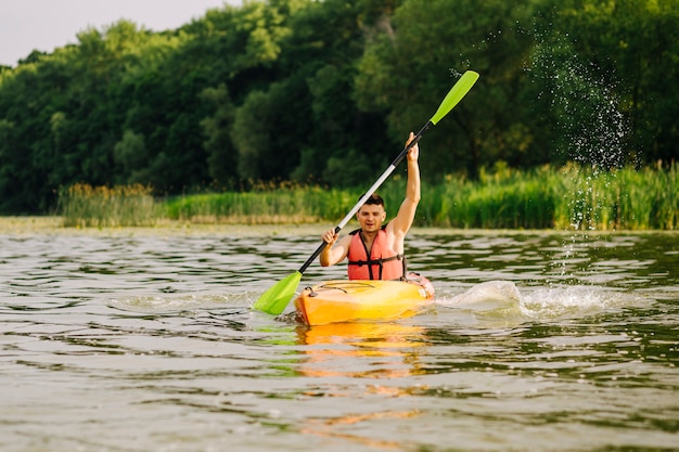 Młody człowiek paddling kajak z dużą ilością plam nad jeziorem