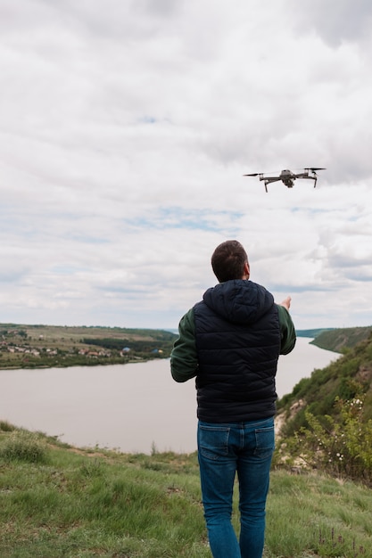 Bezpłatne zdjęcie młody człowiek pilotuje drona w przyrodzie