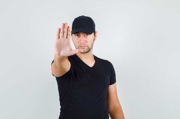 Bezpłatne zdjęcie młody człowiek pokazuje gest stop w czarnej koszulce