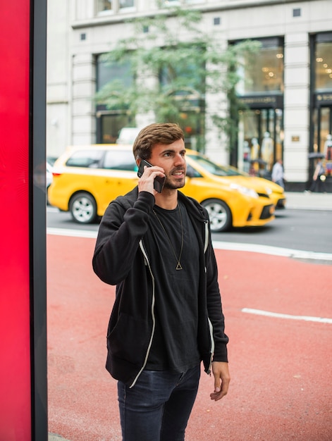 Bezpłatne zdjęcie młody człowiek rozmawia przez telefon na ulicy