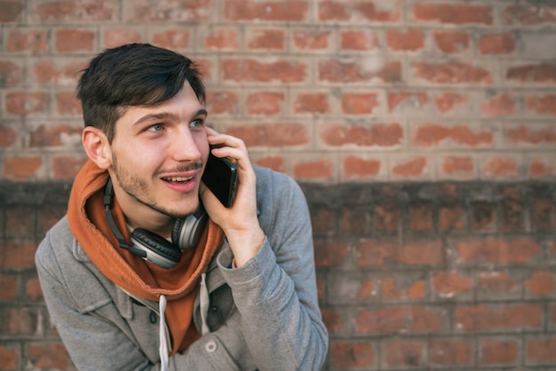 Młody człowiek rozmawia przez telefon na zewnątrz.