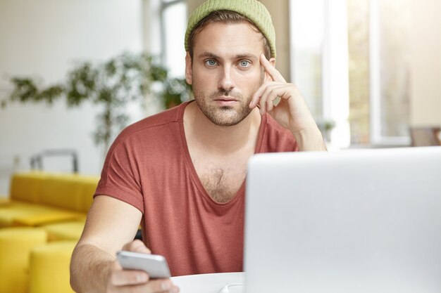 Młody człowiek siedzi w kawiarni z laptopem