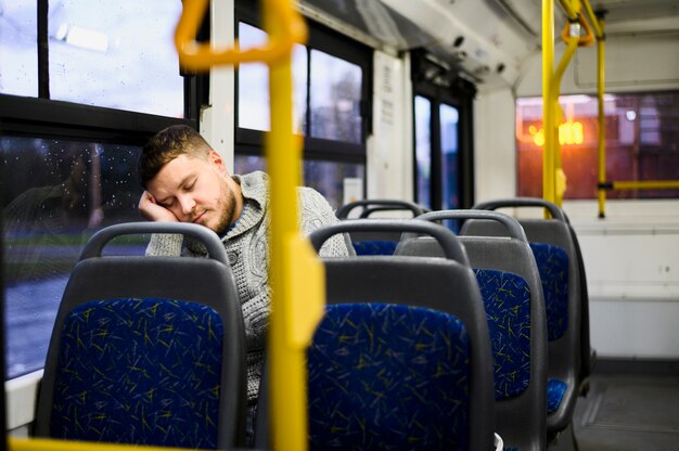 Młody człowiek śpi na siedzeniu autobusu