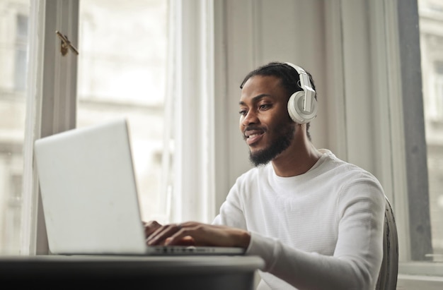 Bezpłatne zdjęcie młody człowiek studiuje z komputerem, słuchając muzyki