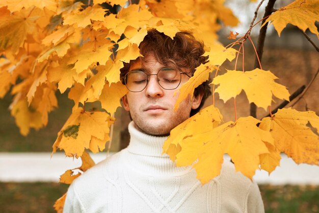 Młody człowiek stwarzających w jesiennych liściach