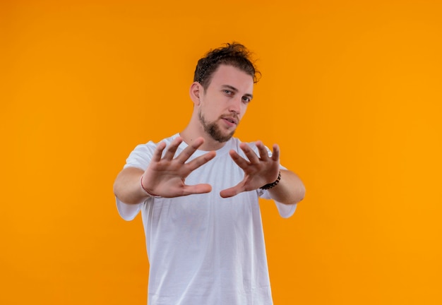 młody człowiek ubrany w białą koszulkę pokazujący gest stopu na odizolowanej pomarańczowej ścianie