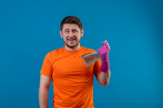 Młody Człowiek Ubrany W Pomarańczowy T-shirt I Rękawice Gumowe, Trzymając Spray Do Czyszczenia