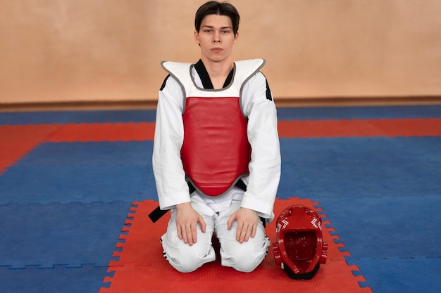 Bezpłatne zdjęcie młody człowiek uprawiający taekwondo w sali gimnastycznej