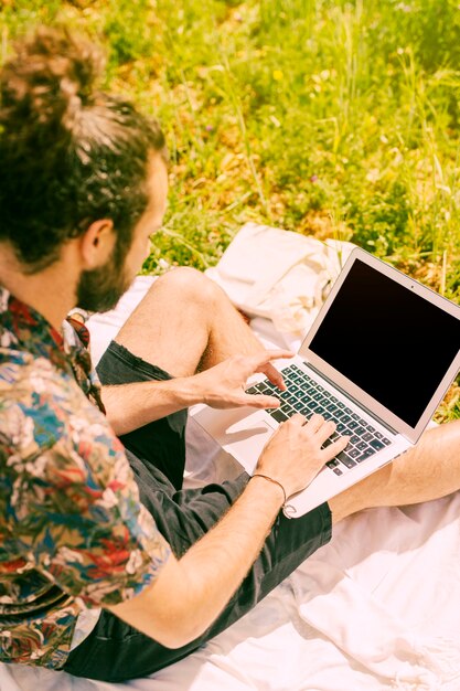 Młody człowiek używa laptop na naturze