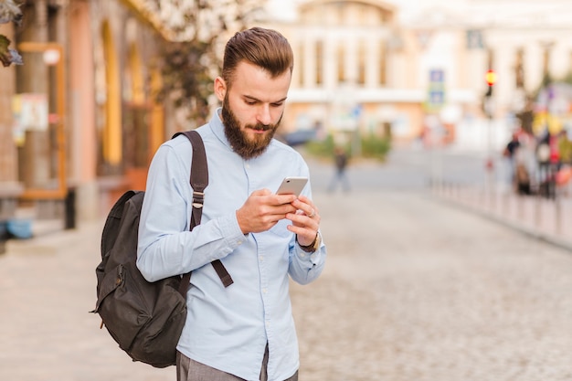 Młody człowiek używa telefon komórkowego przy outdoors