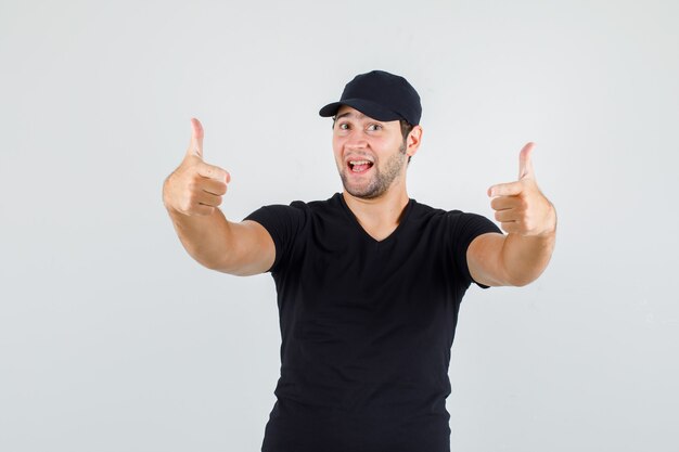 Młody człowiek w czarnej koszulce, czapce pokazującej gest pistoletu i wyglądającej wesoło