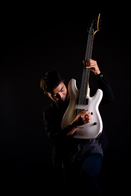 Bezpłatne zdjęcie młody człowiek w czarnej skórzanej kurtce z gitarą elektryczną