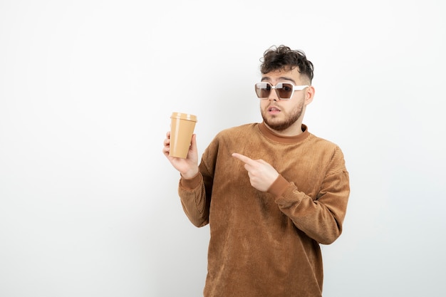 młody człowiek w okularach, trzymając filiżankę kawy.