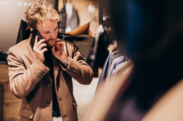Młody człowiek w sklepie z odzieżą męską rozmawia przez telefon