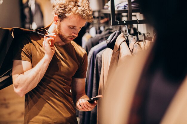 Młody człowiek w sklepie z odzieżą męską rozmawia przez telefon