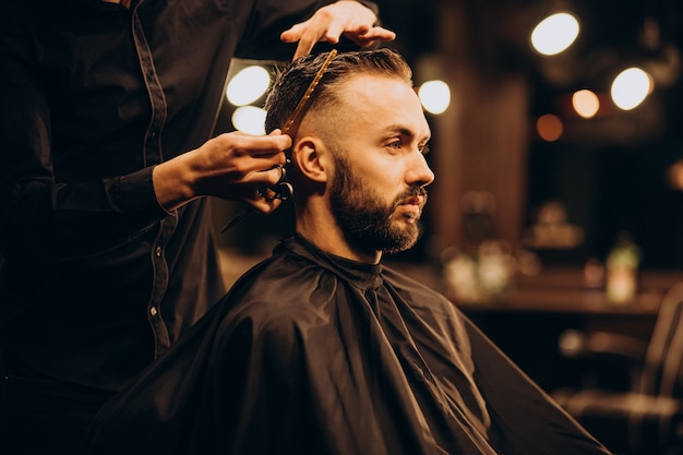 Młody człowiek w zakładzie fryzjerskim przycinanie włosów