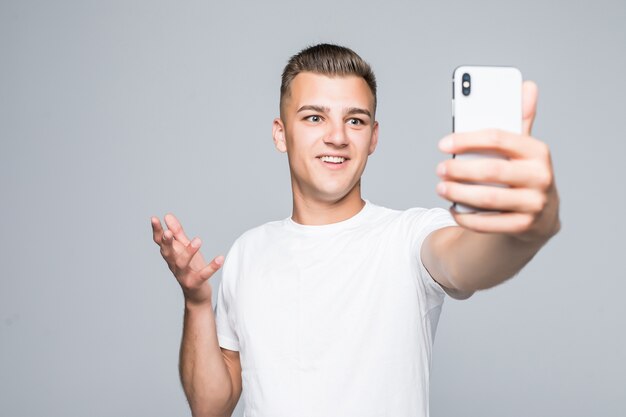Młody człowiek wziąć selfie na szarym tle