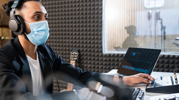 Młody człowiek z maską medyczną pracuje w stacji radiowej