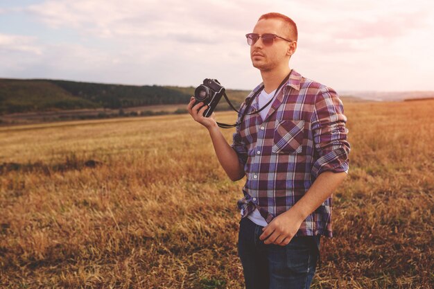 Młody człowiek z retro aparat fotograficzny hipster zewnątrz stylu życia