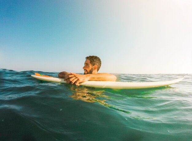 Młody człowiek z surfboard w błękitnym morzu