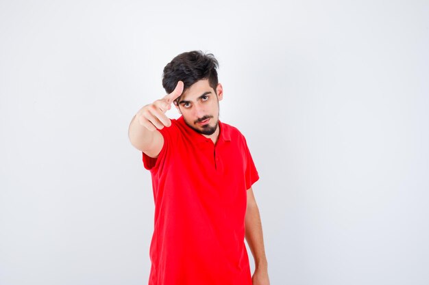 Młody człowiek zapraszający w czerwonej koszulce i wyglądający poważnie