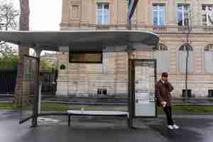 Bezpłatne zdjęcie młody francuz czeka na dworcu na autobus i rozmawia przez smartfona