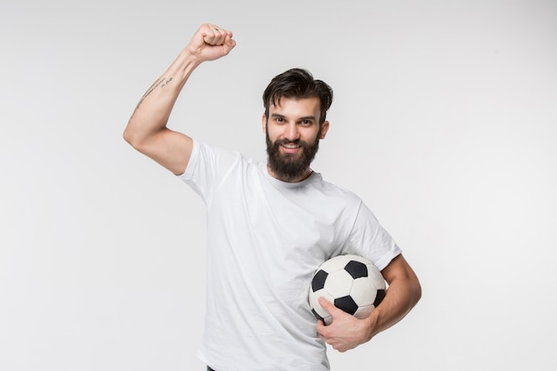 Młody gracz piłki nożnej z piłką przed biel ścianą
