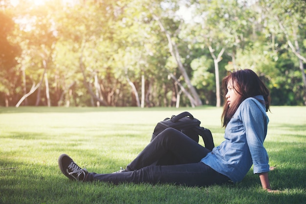 Młody hipster kobiety leżącej na zielonej trawie z plecaka.
