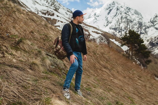 Młody hipster mężczyzna siedzi w górach