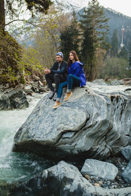 Młody hipster piękna para zakochanych, chodzenie po skałach nad rzeką w zimowym lesie