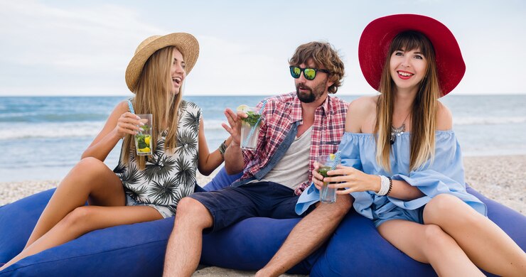Bezpłatny plik Zdjęcie młody hipster towarzystwo przyjaciół na wakacjach, siedząc na plaży na workach fasoli