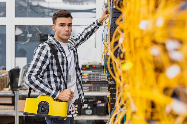 Młody inżynier sieci ze skrzynką pracującą przy przełącznikach Ethernet