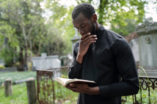 Młody ksiądz mężczyzna trzymający Biblię na cmentarzu