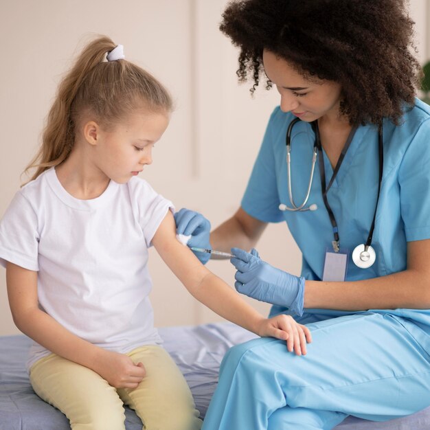 Młody lekarz szczepi małą dziewczynkę
