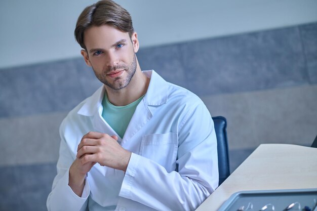 Młody lekarz w fartuchu laboratoryjnym wygląda na zamyślony