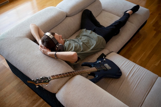 Bezpłatne zdjęcie młody mężczyzna gra na gitarze w domu