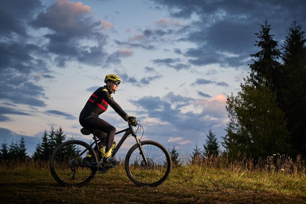 Młody mężczyzna jedzie na rowerze górskim o zachodzie słońca